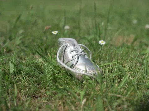 Silver baby shoe on grass - from front Foto stock