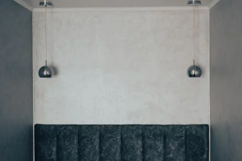 Silver ball shaped lusters hang over sofa near grey wall Stock Photos