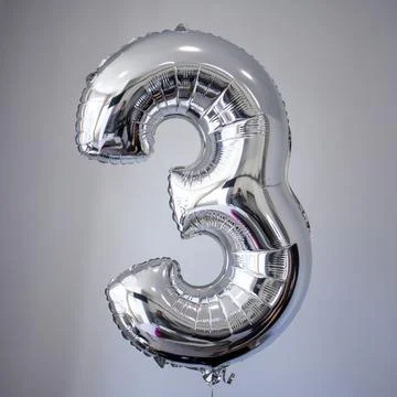 Silver balloon shape of figure three 3 with helium inside on a gray background Stock-Fotos