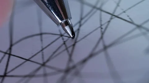 A silver ballpoint pen tip touching down on white paper ruled with a grid. Stock Footage 321213883