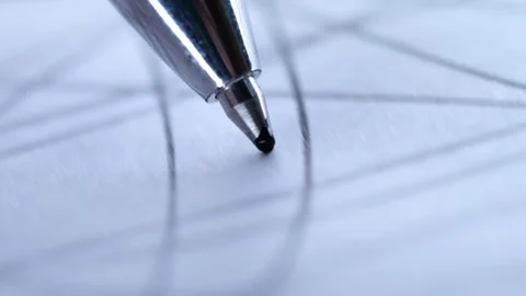 A silver ballpoint pen tip touching down on white paper ruled with a grid. Stock Footage 321213897