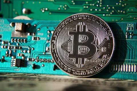 Silver bitcoin coin in front of computer motherboard, cryptocurrency mining 库存照片