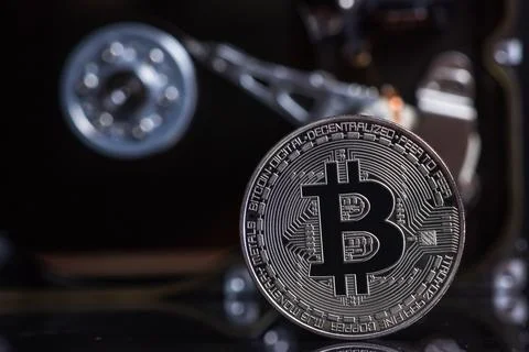 Silver Bitcoin coin on the opened HDD disk. Electronic money, cryptocurrency. Stock Photos