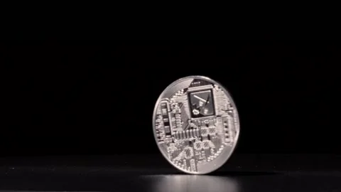 Silver bitcoin spinning in slow motion against black background until it Stock Footage 217946992