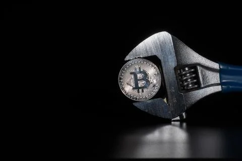 Silver bitcoin in wrench with reflection. Electronic money, cryptocurrency. Stock Photos