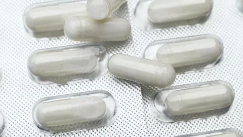 Silver blister pack with white pharmaceutical capsules, rotation in circle. Stockbeeldmateriaal 252796974