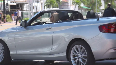 Silver BMW convertible driving down city street Stock Footage 342563242