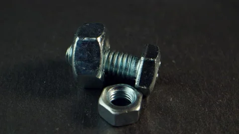 Silver bolts and nuts close-up on a dark background spin with iridescent Stock Footage 170379363