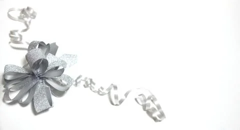 A silver bow with ribbons, which is located on a white background in the corner Stock Photos