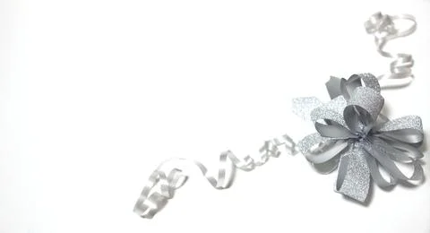 A silver bow with ribbons, which is located on a white background in the corner Stock Photos