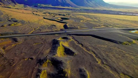 Silver car driving along highway through vast volcanic plains in Iceland Stock Footage 343695872