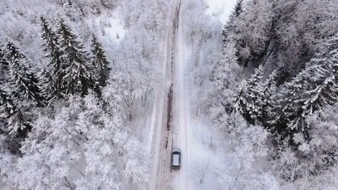 Silver car driving on winter country road in snowy forest, aerial view from dron Stock Footage 71556931