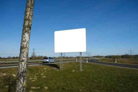 Silver car passing an empty mockup billboard at a german highway Stock Photos