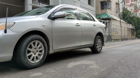 A silver car passing in the paved road Stock Footage 161773394