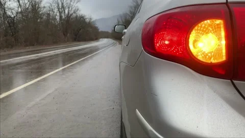 Silver car staying on the side of wet road rainy day with turn signal blinking Stock Footage 146254987