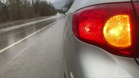 Silver car staying on the side of wet road rainy day with turn signal blinking Stock Footage 146254988