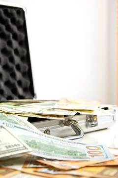 A silver case is open, spilling out US dollar bills Stock Photos