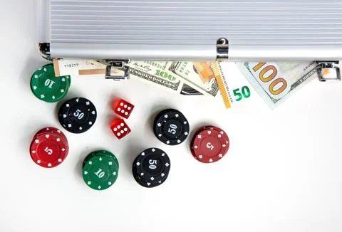 A silver case sits open revealing poker chips, dice, and US dollar bills Stock-Fotos