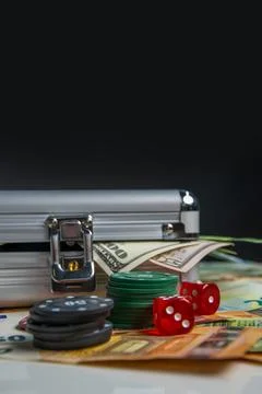 A silver case sits on a table with stacks of poker chips, dice, and cash sp.. Stock Photos
