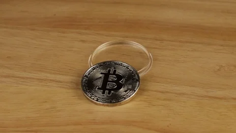 Silver coin bitcoin rotates 360 degrees on a wooden platform Stock Footage 119843472