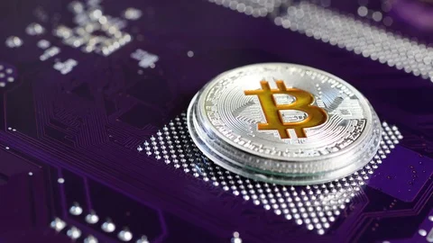 The silver coin bitcoin rotates against the microchip. Stock Footage 86739613