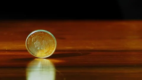 Silver coin spinning on table in slow motion Stock Footage 313633579