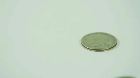 Silver coins falling and spinning on bright white surface Stock Footage 329596061