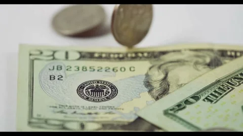 Silver coins falling onto twenty dollar bills close up Stock Footage 329595884