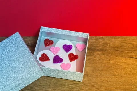 Silver color open box with heart symbols inside Foto stock