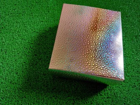 Silver colored box with rainbow shade isolated on green background. Gift box, Stock Photos