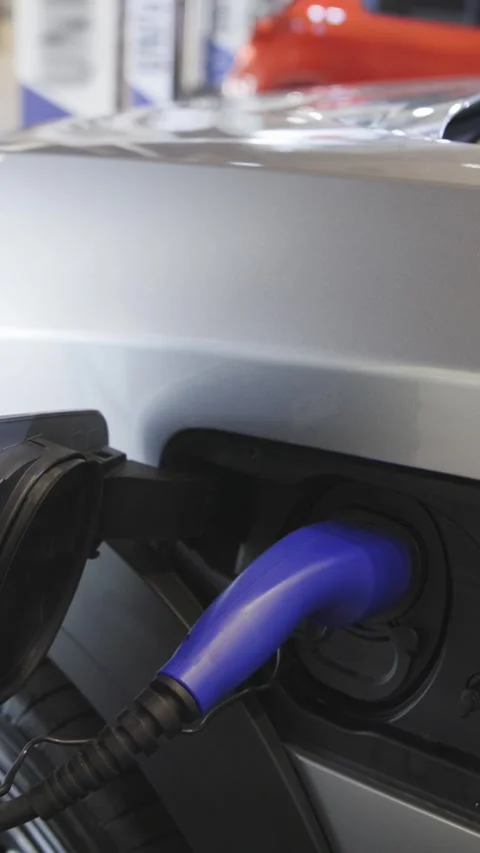 Silver colored electrocar on charge at the charging station indoors Stock Footage 328452431