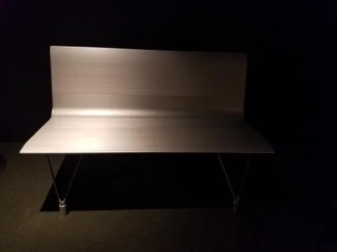Silver colored metal bench half in the dark Stock Photos