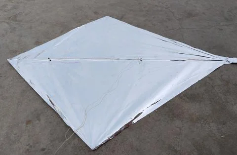 Silver colour plastic kite placed on a concrete floor. Stock Photos