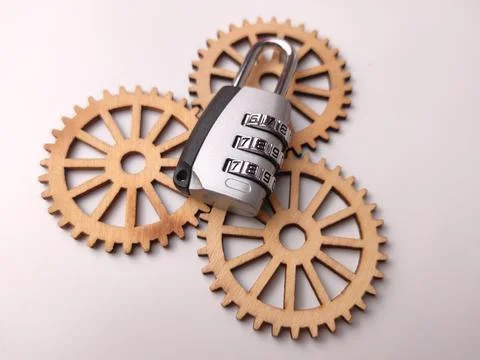 A silver combination padlock rests on top of three interconnected wooden ge.. 库存照片