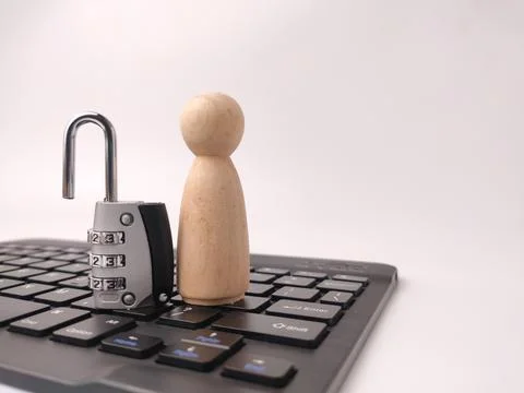 A silver combination padlock stands upright next to a simple wooden peg dol.. Stock Photos