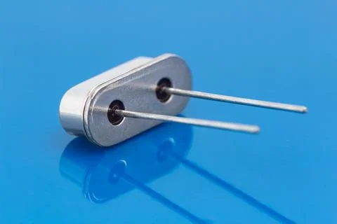 Silver component with two metal pins rests on blue surface Stock Photos