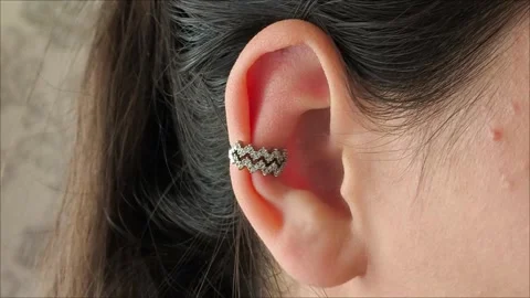 Silver cuff with precious stones in the ear of a brunette girl Stock Footage 311993239