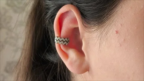 Silver cuff with precious stones in the ear of a brunette girl Stock Footage 311993248