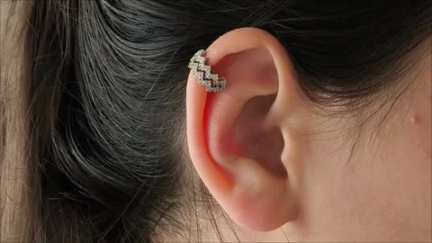 Silver cuff with precious stones in the ear of a brunette girl Stock Footage 311993363