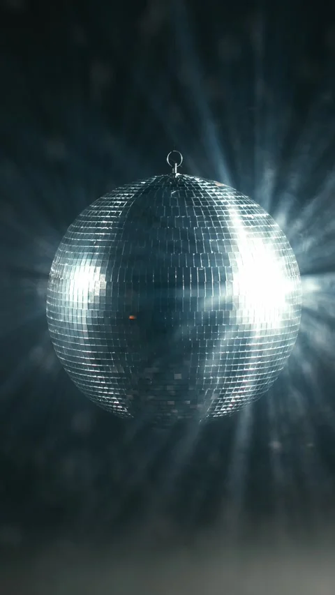 Silver disco ball slowly rotating on a hanging hook, reflecting bright studio Stock Footage 347735008