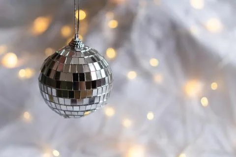 Silver disco ball on a soft background with yellow bokeh of the garland. Light Stock Photos