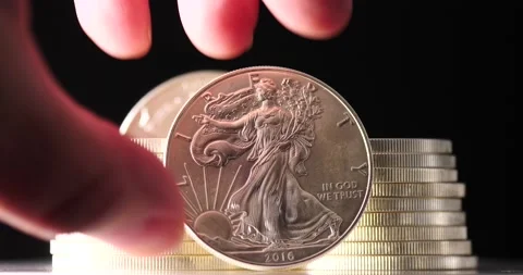 Silver eagle coin being placed down by man and shown isolated on black Stock Footage 207649774