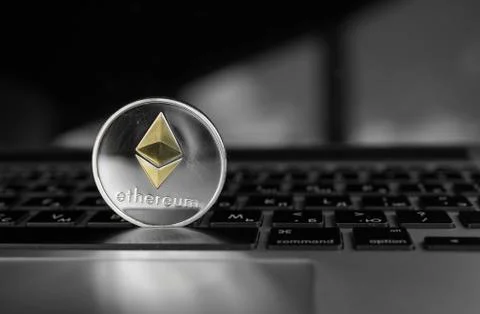 Silver Ethereum coin with gold Ethereum symbol on a laptop keyboard. Exchange Stock Photos