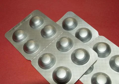 Silver foil pill packaging on red table Stock Photos