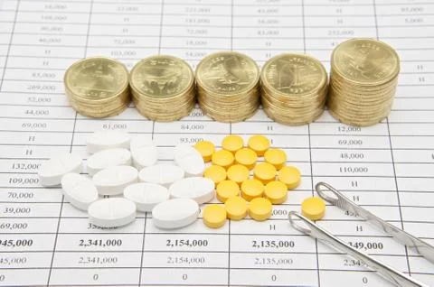 Silver forceps and pill with step pile of gold coins Stock Photos