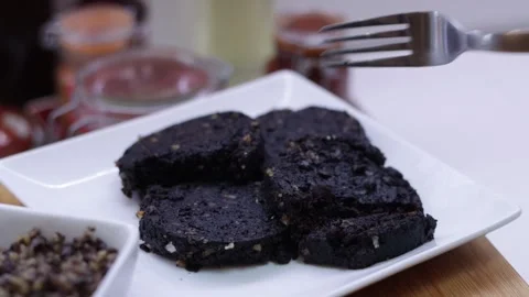 Silver fork cutting a piece of black pudding food Stock Footage 328716168