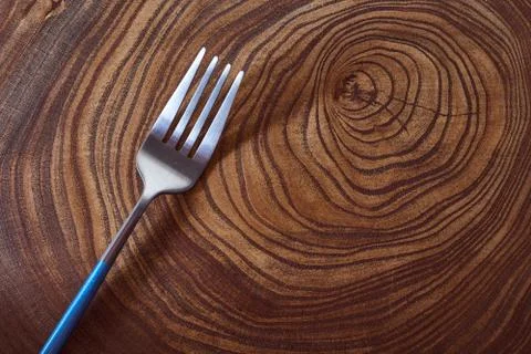 The silver fork lies on a slice of a tree. wooden table. With copy space. Stock Photos
