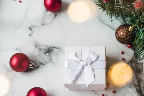 Silver gift on marble background with red Christmas balls and Christmas wre.. Stock Photos