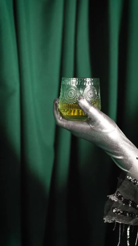 Silver gloved hand showcasing glass of amber liquor Stock-Footage 345857076