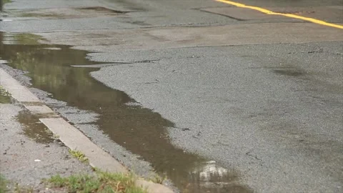 Silver gray car driving by large puddle on wet road and not hitting it Stock Footage 247753217